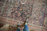 Scalloped navy medallion with intricate arabesques in terracotta and blue on an antique Kermanshah.