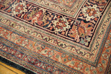 Intricate arabesque borders of an antique Kermanshah carpet in navy, terracotta, and powder blue.