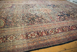 Close view of the low pile across the elaborate terracotta and navy borders of an antique Kermanshah carpet.