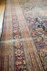 A long perspective showing the detailed floral borders and time-softened pile of an antique Kermanshah carpet.