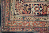 Corner of an antique Kermanshah carpet with intricate arabesque borders in terracotta, ivory, and navy.
