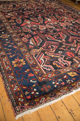 Vintage Baktiari carpet corner, dark navy border with red, sky blue, ivory floral motifs, and fringe.