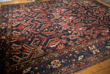 Close-up of hand-knotted Baktiari carpet pile, showcasing red, navy, ivory serrated leaf pattern.