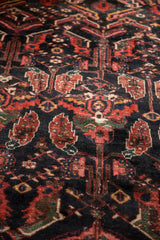 Vintage Baktiari carpet: large serrated leaves, red floral blossoms, dark navy field.