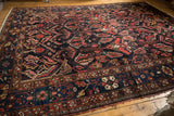 Persian Baktiari carpet detail: dark navy field, cherry red serrated leaves, floral blossoms.