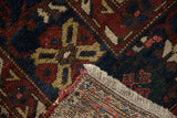 Hand-knotted Baktiari carpet showing cherry red, navy floral pattern, woven foundation, and fringe.