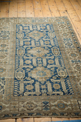 Antique Shirvan rug corner with geometric serrated leaves in navy blue and ivory, visible wear.