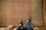 A perspective view of the even wear and detailed seed motifs on an antique striped Senneh rug.
