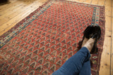 Madder root red field with allover boteh design and characteristic antique wear.