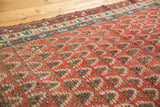 Antique Caucasian rug close-up: madder red boteh pattern, geometric border, visible wear.