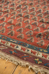 Aubergine border of the antique Caucasian runner featuring red, blue geometric motifs and macrame fringe.