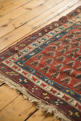 Corner of antique Caucasian runner, featuring madder red field, sky blue, aubergine borders, and a fringed macrame end.