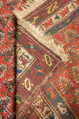 Intact beige selvage on antique Caucasian runner, revealing geometric aubergine border and madder red field.
