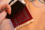 Maroon Bokhara CoasterRug with intricate geometric pattern, contrasting cream fringe and dark rubber backing.