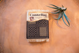 Bògòlanfini Mudcloth CoasterRug with sharp black, cream geometric patterns, and white fringe.