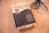 Bògòlanfini Mudcloth Coaster with crisp black and off-white geometric patterns and fringe.