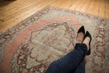 Vintage distressed Oushak rug section with geometric starburst motif, pale blush, seafoam green.