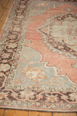 Distressed Oushak carpet with blush, blue, charcoal tones, showing mostly even wear.