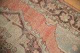 Distressed Oushak carpet detail, showing pale blush and charcoal motifs with wear to knot heads.