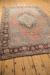 Distressed vintage Oushak rug corner, highlighting pale blush and charcoal border patterns.