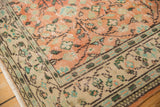 Distressed apricot blush field meets ivory border with sea foam green motifs on vintage Oushak.