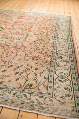 Distressed apricot blush Oushak rug corner, with ivory fringe and scrolling vinery.