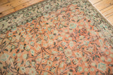 Distressed apricot blush Oushak carpet with scrolling vinery, sea foam green, and visible wear.