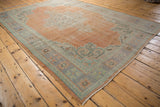 Corner of a distressed Vintage Oushak rug with worn apricot field and pale blue spandrel.