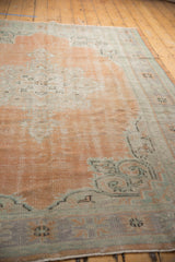 Evenly worn texture of a distressed Oushak rug in apricot blush and sea foam.