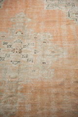 Vintage distressed Oushak rug texture, showcasing faded apricot blush and ivory pile with visible foundation.