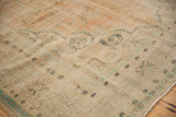 Worn texture of a distressed Oushak carpet, revealing foundation, faded apricot, and green floral motifs.