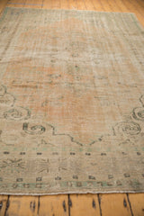 Distressed Oushak carpet's lower border, revealing even wear and foundation in apricot and ivory.