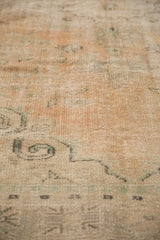 Distressed Oushak rug texture with visible foundation, showing pale apricot and green.