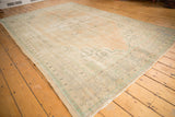 Distressed vintage Oushak carpet corner with even wear, foundation showing, and pastel tones.