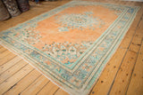 Distressed vintage Oushak carpet with faded apricot, mint green floral patterns and soft wear.