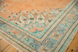 Faded apricot Oushak rug corner with distressed pile, showing mint and blue floral border.