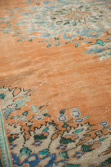 Visible foundation and worn pile texture on a distressed apricot Oushak rug with faded floral motifs.