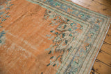 Distressed Oushak corner detail: apricot orange field, faded mint floral motifs, visible wear.