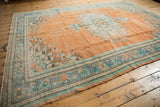 Worn apricot field and faded floral borders on a distressed vintage Oushak rug corner.