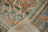 Distressed Turkish Oushak rug corner, with worn apricot and mint pile, revealing its hand-knotted reverse.