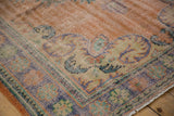 Distressed Oushak corner with worn Rococo vinery, soft apricot, pale blue, and mint green.