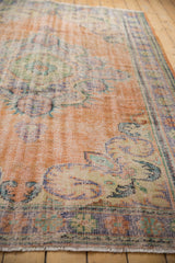 Decorative distressed Oushak rug with worn apricot orange pile and pale blue Rococo vinery.
