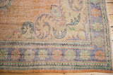 Distressed Oushak rug border detail with soft apricot, ivory, blue, green, and foundation wear.