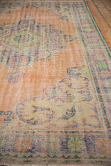 Distressed vintage Oushak rug texture, showing faded apricot, pale blue, and mint green.