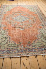 Distressed hand-knotted Oushak pile with brick red and pale blue, foundation showing.