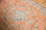 Distressed Oushak carpet detail: mostly even wear, pale terra cotta field, faded blue floral vinery.