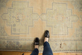 Distressed Oushak runner with geometric medallion, floral cross sections, sand, and pale green tones.
