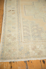 Distressed Oushak rug corner with stepped spandrels, germinating plant motif, and worn pile texture.