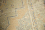 Textural close-up of distressed Oushak rug, showing mostly even wear and geometric patterns in sand, pale green.