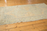 Distressed sand field and worn pale green geometric motifs on a vintage Oushak runner.